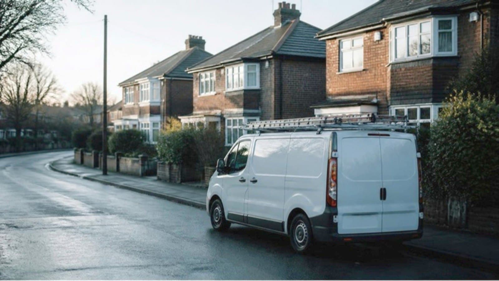 A white van parked on a residential street at first light